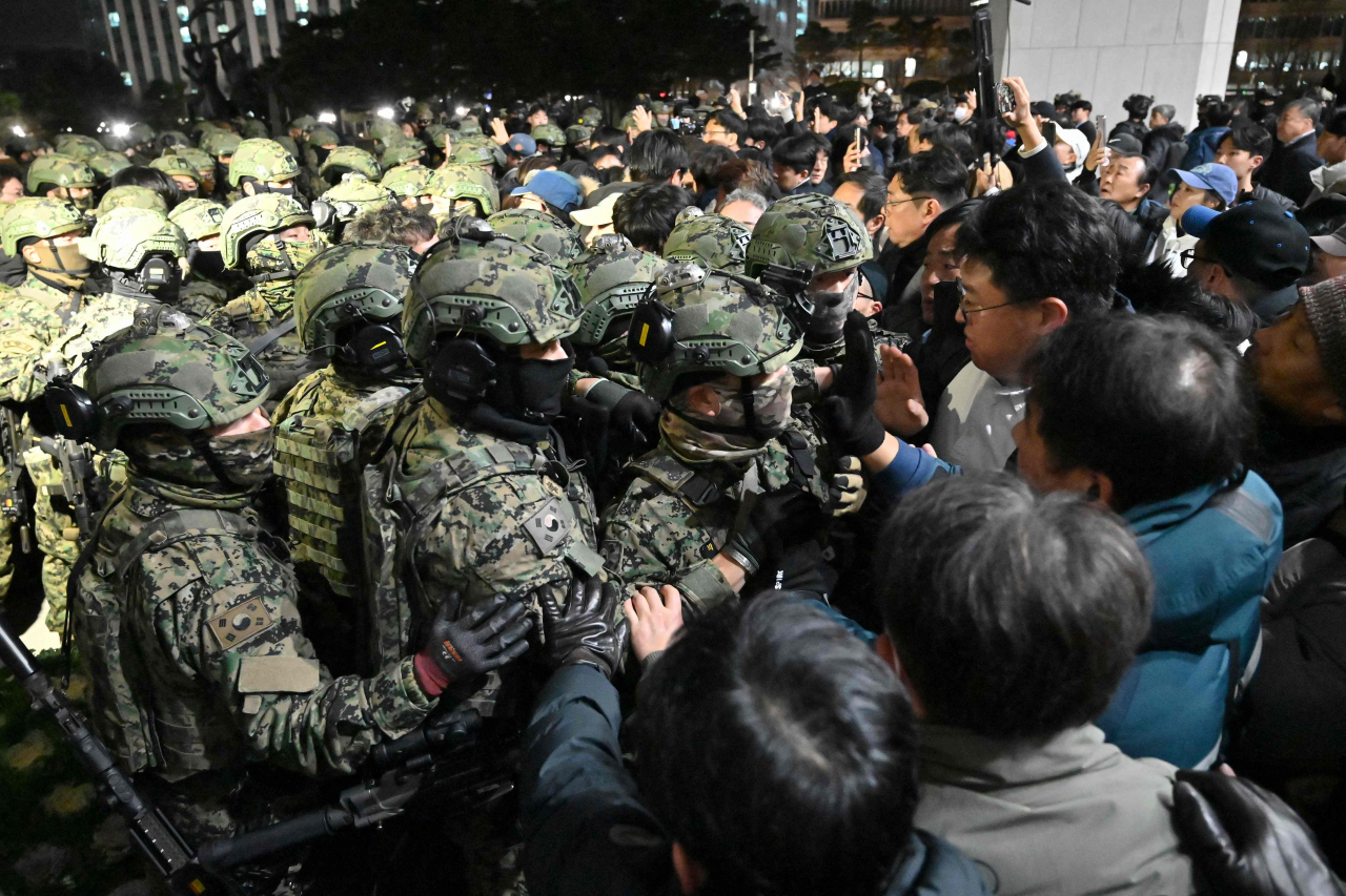 Soldiers try to enter the National Assembly building in Seoul on Dec. 4 after South Korea President Yoon Suk Yeol declared martial law. South Korea's President Yoon Suk Yeol on Dec. 3 declared martial law, accusing the opposition of being 