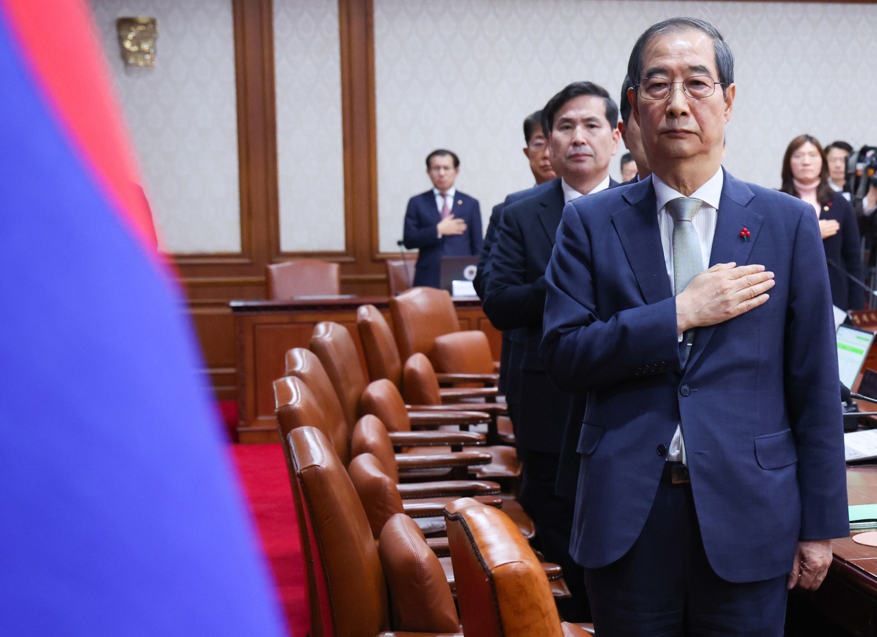 Acting President Han Duck-soo salutes the national flag before convening a Cabinet meeting on Thursday at the Seoul Government Complex. (Yonhap).