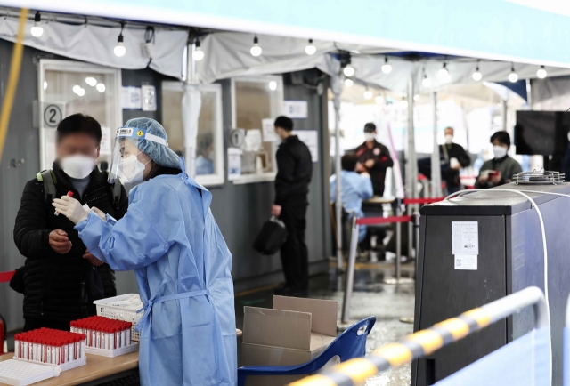 People wait in line to take COVID-19 tests at a makeshift testing center in front of Seoul Station in central Seoul on Saturday. South Korea reported 335,580 new COVID-19 infections that day, bringing the total caseload to 11,497,711, according to the Korea Disease Control and Prevention Agency. (Yonhap)