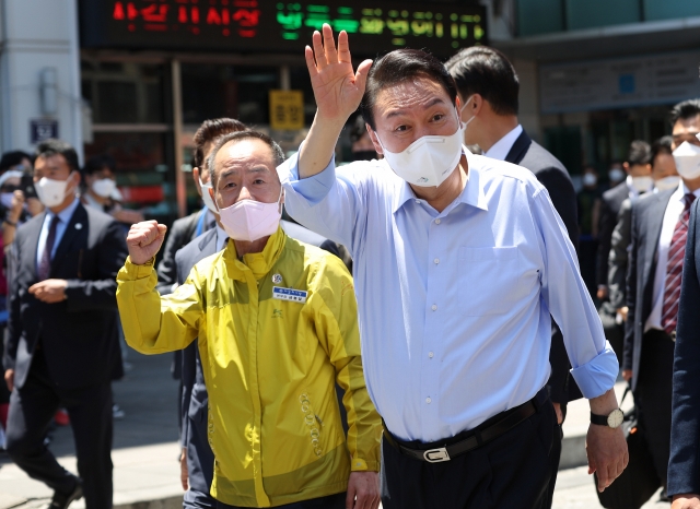 This photo, provided by the presidential office, shows President Yoon Suk-yeol (R) greeting citizens during a visit to a traditional market in the southeastern city of Busan on Tuesday. (The presidential office)