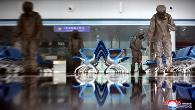 Quarantine officials spray disinfectant at Pyongyang International Airport in the North Korean capital amid the highest-level alert on the coronavirus, in this undated photo released by the North's Korean Central News Agency on June 10. (KCNA)