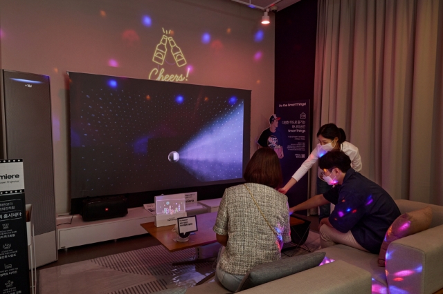 A promotional photo of users experiencing connectivity of SmartThings apps and a Samsung TV. (Samsung Electronics)