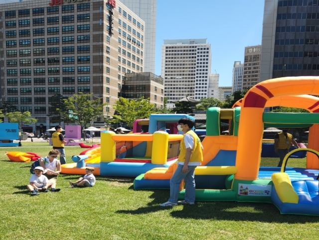 A woman and her two sons get ready to play in an inflatable bounce house. (Choi Jae-hee / The Korea Herald)