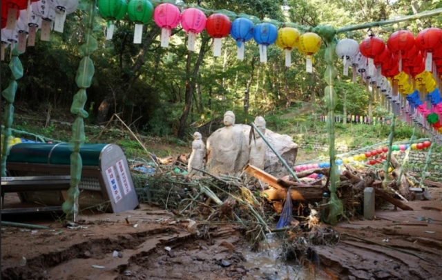 Stone Buddhas in Four Directions stand amidst debris of a mudslide. (Yonhap)