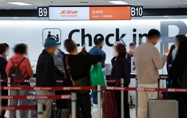 This photo taken Sunday shows people waiting in line to leave for Osaka, Japan, at Gimpo International Airport in western Seoul amid eased virus curbs. (Yonhap)