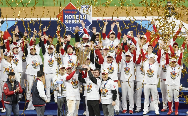 Shinsegae Group Vice Chairman Chung Yong-jin, center, who also owns the SSG Landers, holds the trophy as the members celebrate their Korean Series victory over the Kiwoom Heroes, Tuesday. (Yonhap)