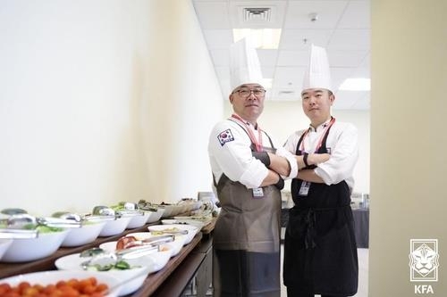 Kim Hyung-chae (left) and Shin Dong-il, chefs for the South Korean men's national football team at the FIFA World Cup in Qatar, pose for photos at the team dining hall at Le Meridien City Center, Doha, the team's official hotel during the tournament on Thursday. (Korea Football Association)