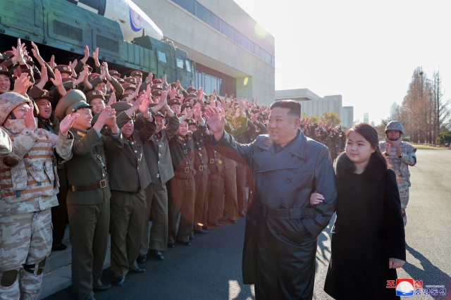 North Korean leader Kim Jong-un (left) walks hand in hand with his daughter, presumed to be his second child, Ju-ae, during a photo session with officials involved in this month's intercontinental ballistic missile launch, in this photo provided (Korean Central News Agency)