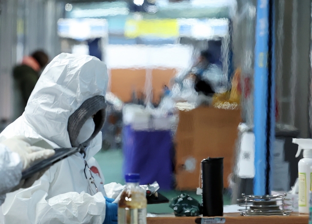 A medical worker stands by a heater at a COVID-19 testing station in Seoul amid a cold wave, last Wednesday. (Yonhap)