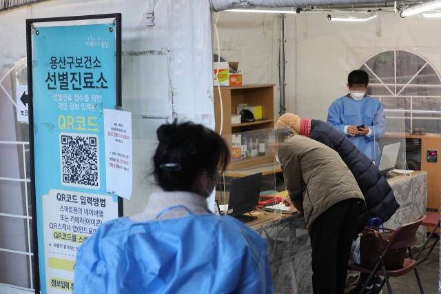 People wait in line at a public health center screening site in Yongsan, central Seoul, Tuesday. (Yonhap)