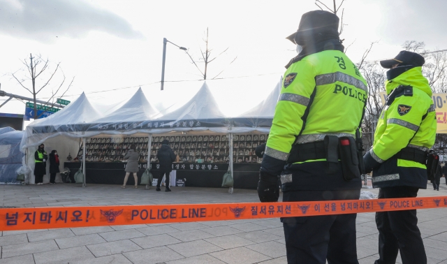 Police officers stand in front of a police line at a mourning altar for Itaewon crown crush victims in Seoul, Thursday. (Yonhap)