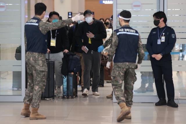 People traveling from China to South Korea are seen following the instruction of the Korean military personnels at Incheon Airport on Monday. (Yonhap)