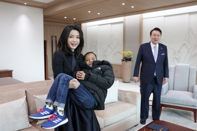 First lady Kim Keon Hee lifts Cambodian boy Aok Rotha who is recovering from heart disease surgery at the presidential office in Yongsan, Seoul, on Tuesday. (Yonhap)