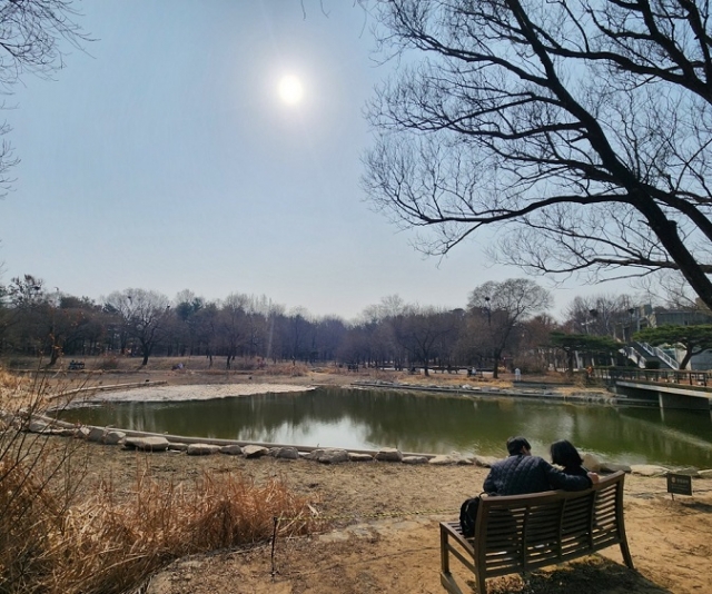 A couple sits on a bench by the lake in Seoul Forest in Seongsu-dong, eastern Seoul. (Choi Jae-hee / The Korea Herald)