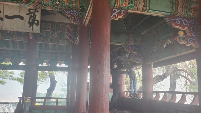 Heritage authorities remove signboards from the Gyeongpodae Pavilion in Gangneung, Gangwon Province, on Tuesday morning as wildfires burned close to the site. (CHA)