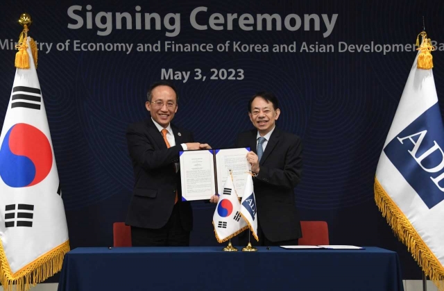 Finance Minister Choo Kyung-ho (left) and Asian Development Bank President Masatsugu Asakawa pose for photos at a meeting held Wednesday. (Ministry of Economy and Finance)