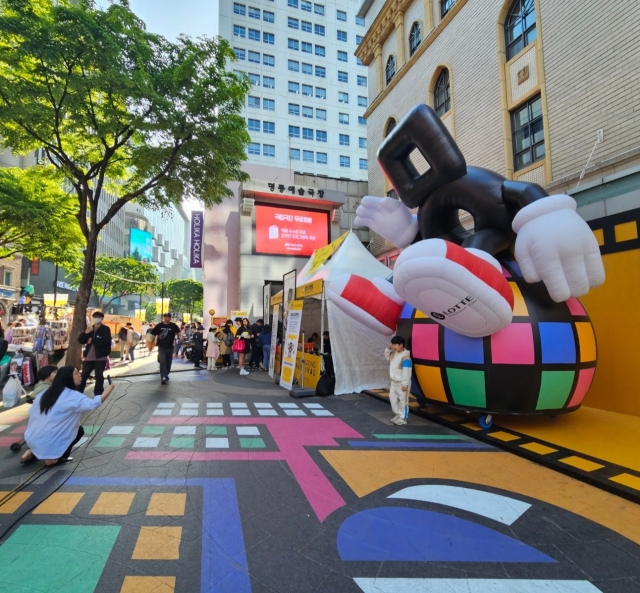 A kid poses in front of the Myeongdong character 