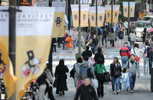 In this file photo, people walk along Myeongdong street in central Seoul without face masks on May 1. (Yonhap)