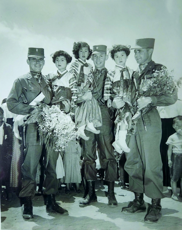 US soldiers pose with children at a ceremony where relief clothing from the US was delivered to Koreans in need on May 29, 1954. (Courtesy of Stephen Spina)