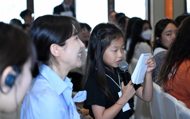 Nine-year-old Ain Jeong, the youngest participant of the forum, asks a question to Ali Tabrizi, director of the Netflix documentary 