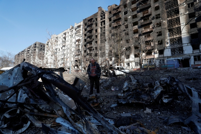 A local resident stands next to the wreckage of his car in the courtyard of an apartment building destroyed in the course of Ukraine-Russia conflict in the besieged southern port city of Mariupol, Ukraine. (Reuters-Yonhap)