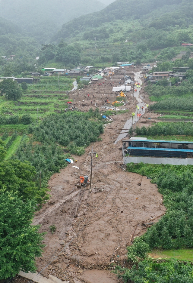 Firefighters conduct rescue operations in a village hit by a landslide in the southeastern county of Yecheon on Saturday. (Yonhap)