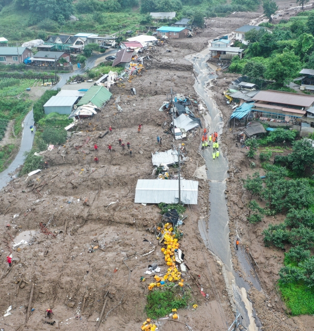 Firefighters conduct rescue operations in a village hit by a landslide in the southeastern county of Yecheon on Saturday.