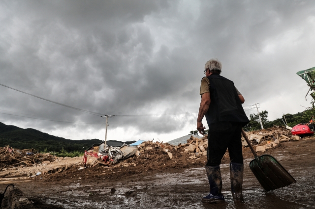 A resident is seen assessing damaged property under approaching rain clouds in the village of Jinpyeong-2-ri, Gamcheon-myeon, Yecheon-gun, North Gyeongsang Province, which was devastated by a landslide triggered by torrential rains on Monday. Yecheon-gun issued safety warnings to residents of areas experiencing heavy downpours once again on the day. (Yonhap)