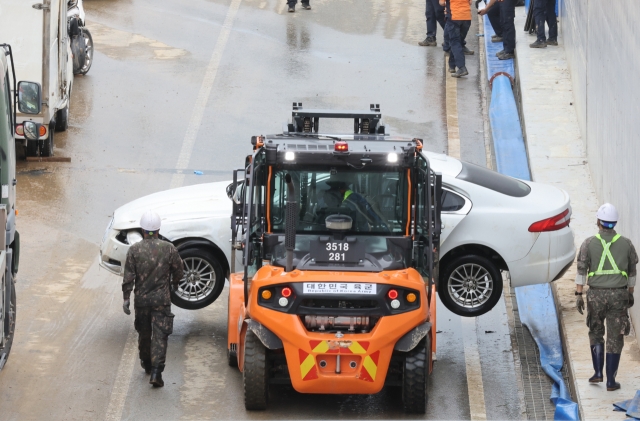 A submerged sedan is being carried by rescue workers as part of the underpass drainage work in Cheongju, North Chungcheong Province, on Monday. (Yonhap)