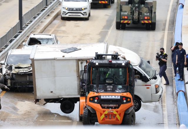 Damaged vehicles are pulled out of a flooded underground tunnel in the town of Osong, North Chungcheong Province, central South Korea, on Monday. (Yonhap)