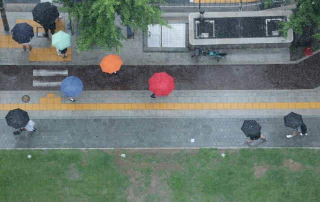 People with umbrellas walk in Jongno-gu, Seoul on July 13. (Yonhap)