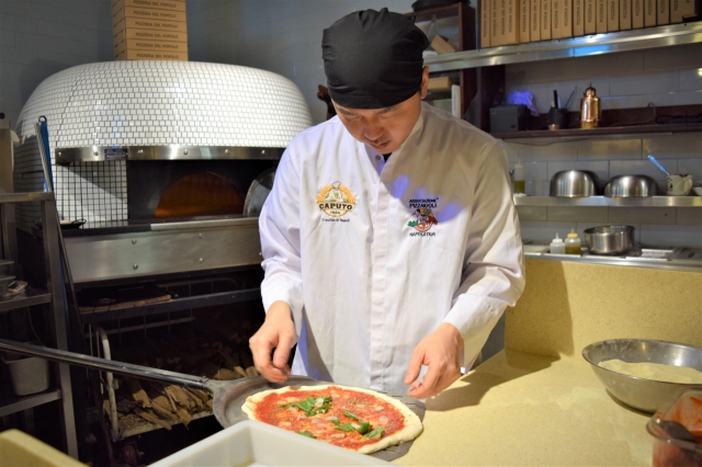 Yu places the pizza on the pizza peel before it goes into the wood-fired pizza oven. (Kim Hae-yeon/ The Korea Herald)