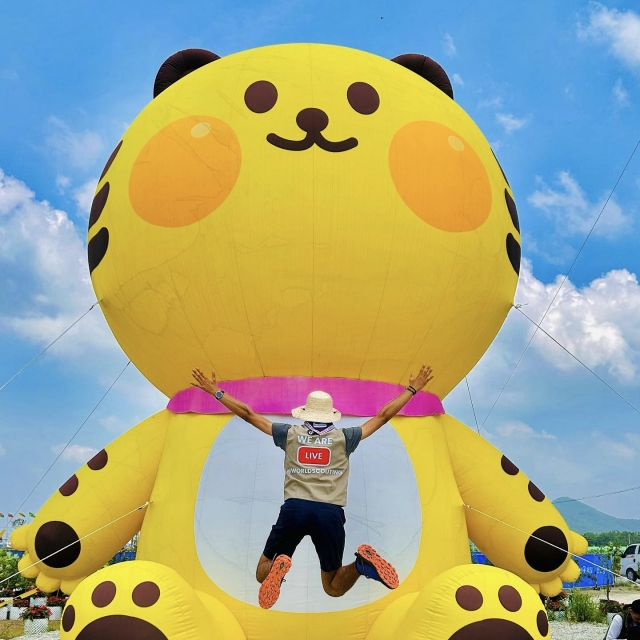 Yassine Gandouz, an International Service Team volunteer from Tunisia, jumps for a photo in front of the 2023 World Scout Jamboree mascot, Saebeomi. (Courtesy of Yassine Gandouz)