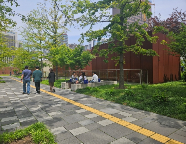 People walk and sit to chat at Seosomun Historic Park during a lunch time on May 10. (Park Yuna/The Korea Herald)