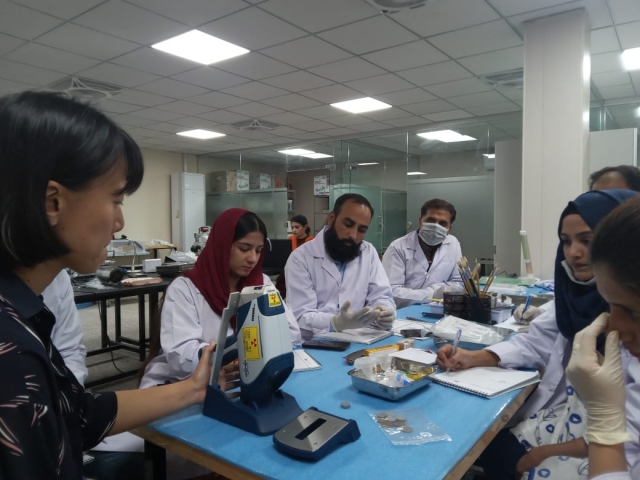 A cultural heritage preservation researcher from the Korea Cultural Heritage Foundation (left) demonstrates a treatment process for gold artifacts to officials in Cambodia in October 2022. (KCHF)