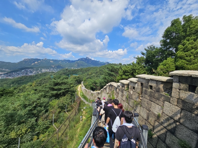 Participants descend toward the Cheongundae Information Center after reaching the peak, Tuesday. (Kim Hae-yeon/The Korea Herald)