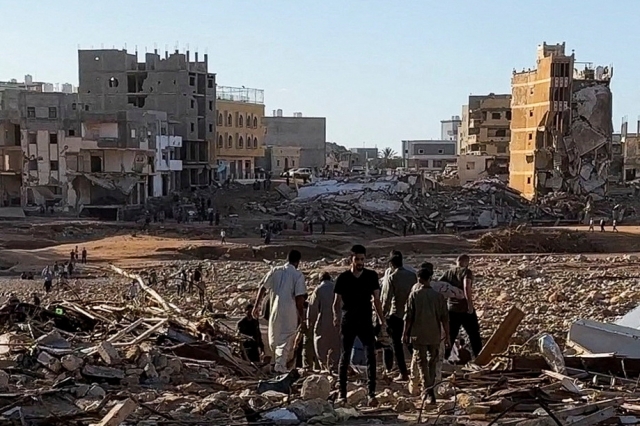 People walk through debris after a powerful storm and heavy rainfall hit Libya, in Derna, Libya, on Tuesday. (Reuters)