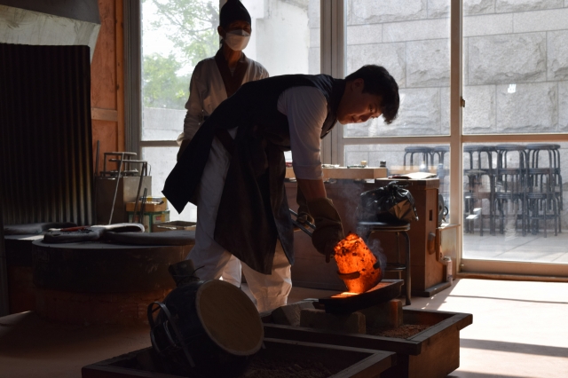 Lim Gyu-heon, a metal printing type master, pours molten metal into the sand mold to demonstrate the making of metal type. (Kim Hae-yeon/ The Korea Herald)