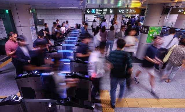 Subway passengers walk between the turnstile gates at City Hall Station in Seoul on Thursday. (Yonhap)