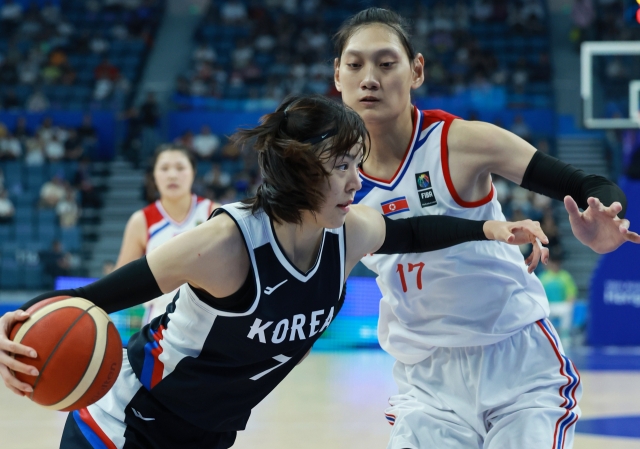 Park Ji-su of South Korea (left) tries to drive past Pak Jin-a of North Korea during the teams' Group C game of the Asian Games at Hangzhou Olympic Sports Centre Gymnasium in Hangzhou, China, on Friday. (Yonhap)