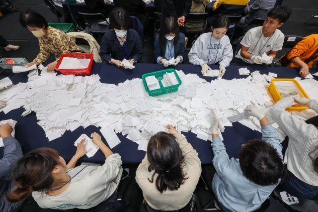 Election officials sort ballot papers to count votes for the Gangseo Ward chief by-election at a sports center in Seoul on Wednesday night. (Yonhap)