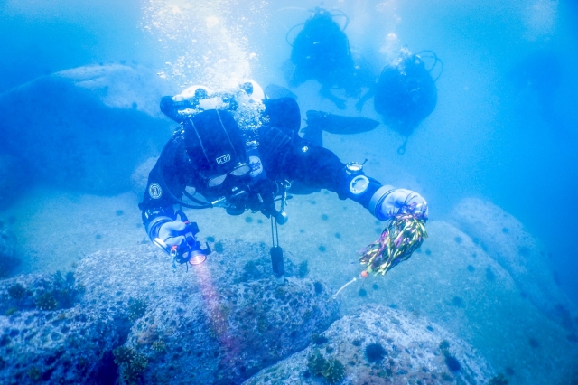 Coway employees dive underwater to collect litter at a beach in Gangwon Province as part of its environmental campaign in July. (Coway)