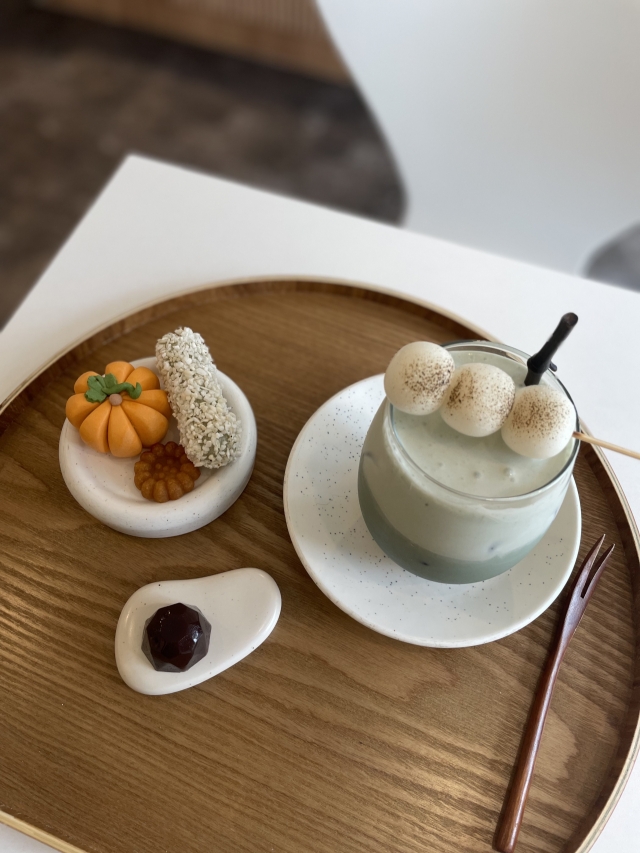 A set of seasonal flower cakes, rice puffs, Yakgwa, red bean jelly and a black sesame latte (Kim Da-sol/The Korea Herald)