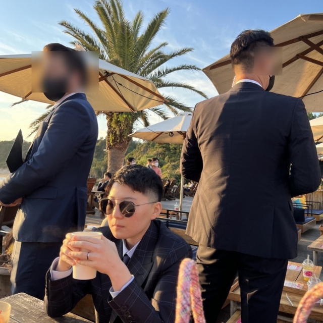 Jeon Cheong-jo sitting at a cafe table next to two men he apparently hired to pose as bodyguards. (Kim Min-seok)