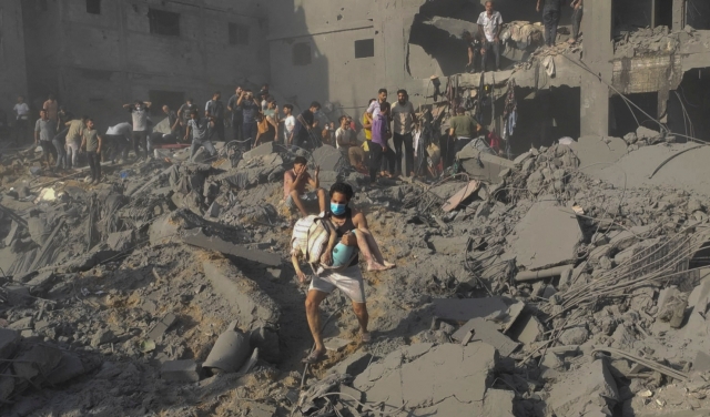 A Palestinian man carries a casualty as others conduct search and rescue works at the site of Israeli strikes on houses in Jabalia refugee camp in the northern Gaza Strip, October 31. (AP-Yonhap)