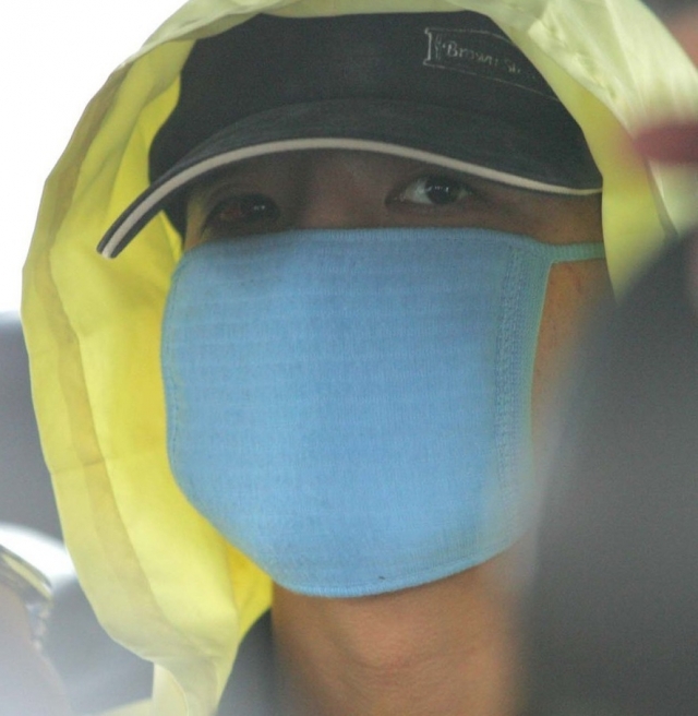 Yoo Young-chul leaves a police station in Seoul to participate in a crime scene reenactment in July 2004. (Yonhap)