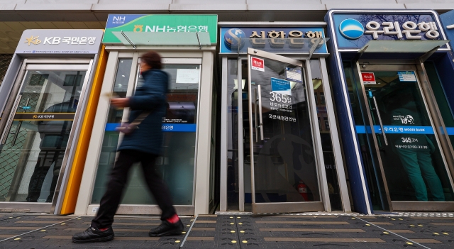 A citizen passes by a row of ATM machines in Seoul, Wednesday. (Yonhap).