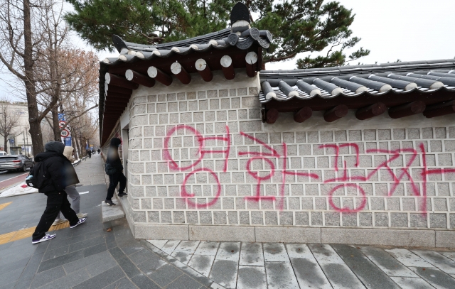 Pedestrians look at red and blue graffiti that reads 