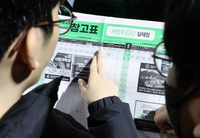 Students look at college admissions data at a private academy briefing session on strategies to successfully enter university. (Yonhap)