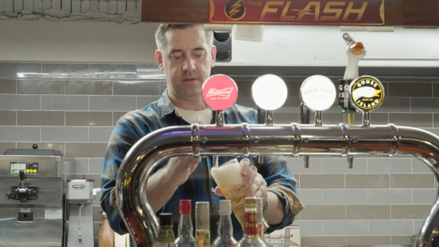 Joey Croner, owner of Dice and Comics Cafe, pours a beer behind the counter. (The Korea Herald)